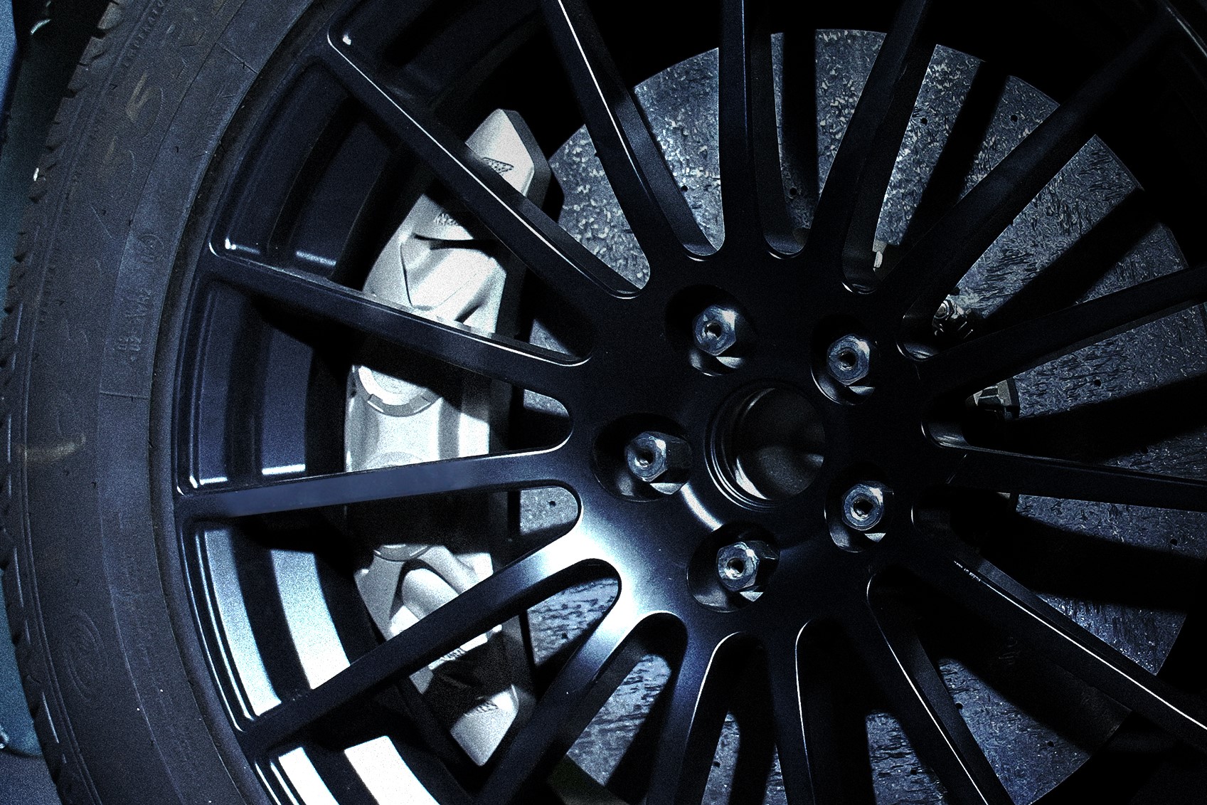 Metal additive manufacturing brake caliper behind mesh-spoke automotive wheel